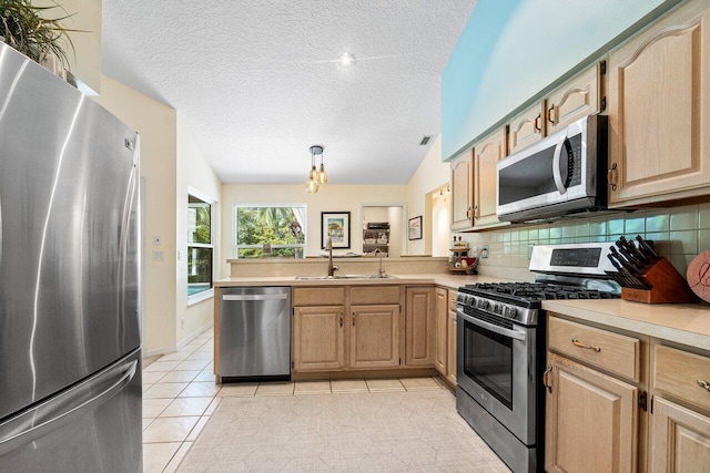 kitchen featuring a textured ceiling, sink, appliances with stainless steel finishes, and tasteful backsplash