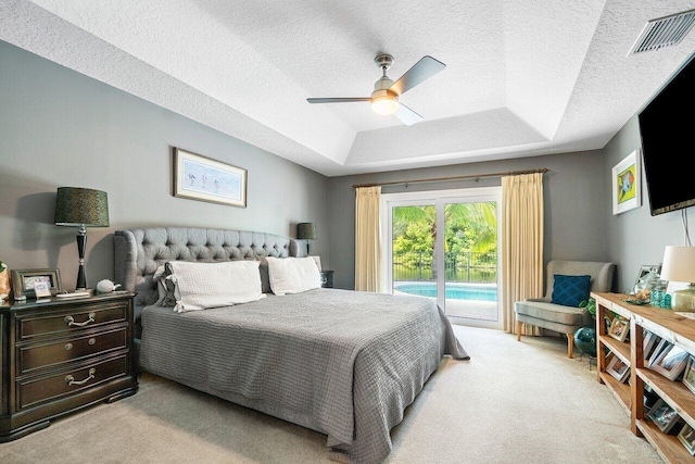 carpeted bedroom featuring ceiling fan, a raised ceiling, access to exterior, and a textured ceiling