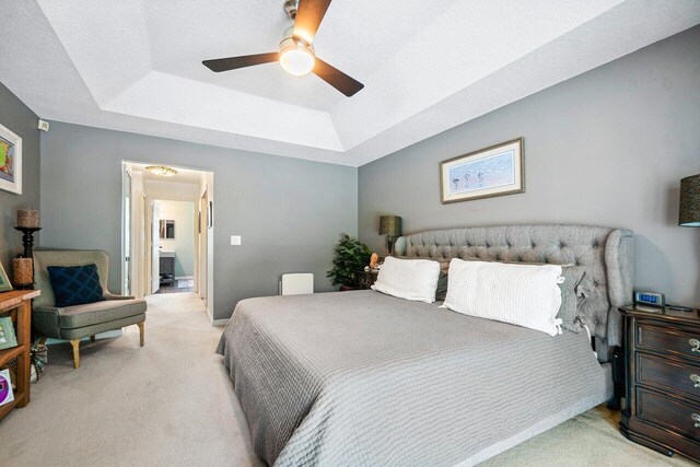 bedroom featuring a tray ceiling, ceiling fan, and light colored carpet