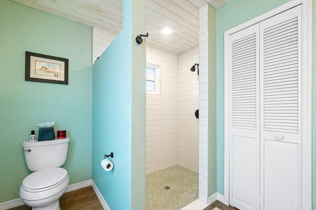 bathroom with tiled shower, hardwood / wood-style floors, and toilet