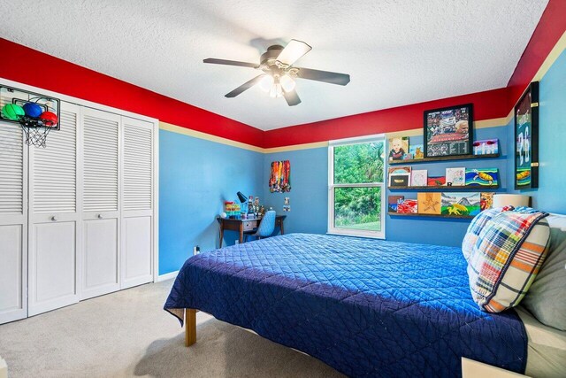 bedroom with a closet, ceiling fan, carpet, and a textured ceiling