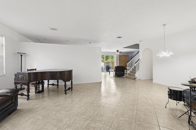 interior space with arched walkways, light tile patterned floors, ceiling fan with notable chandelier, visible vents, and baseboards