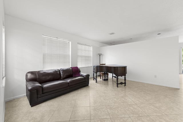 living area featuring light tile patterned floors, visible vents, and baseboards