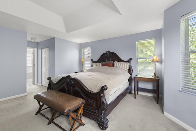 bedroom with light colored carpet, a textured ceiling, and baseboards