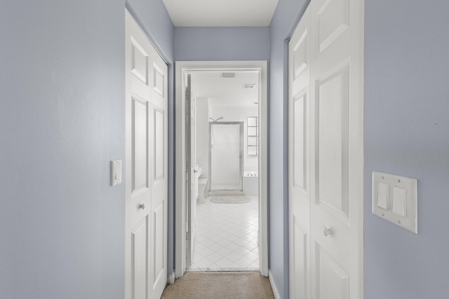 corridor with light carpet, light tile patterned floors, and visible vents