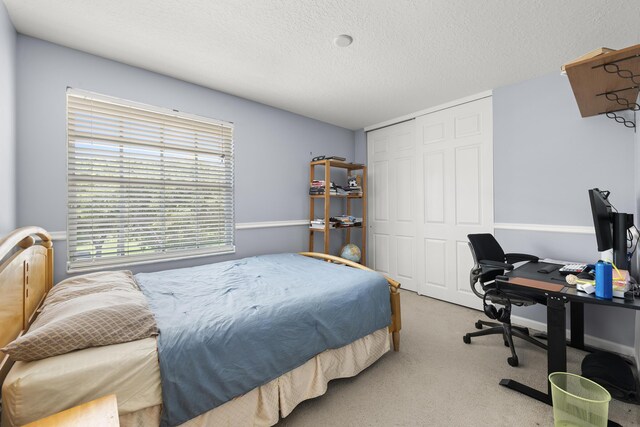 bedroom featuring a textured ceiling, a closet, and light colored carpet