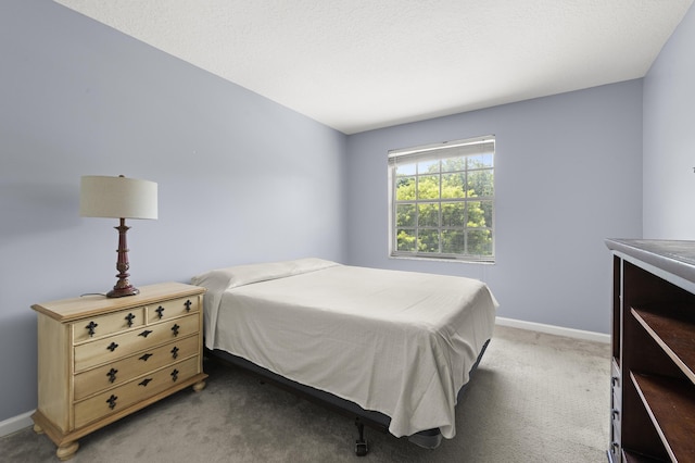 bedroom with a textured ceiling, dark colored carpet, and baseboards