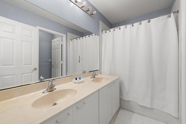 full bath with a textured ceiling, shower / bath combination with curtain, double vanity, and a sink