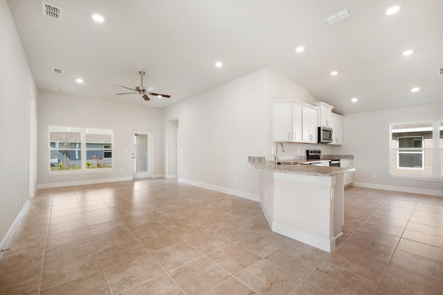 kitchen featuring kitchen peninsula, light stone countertops, stainless steel appliances, ceiling fan, and white cabinetry