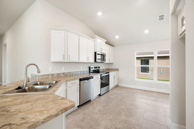 kitchen featuring stainless steel appliances, white cabinetry, lofted ceiling, and sink