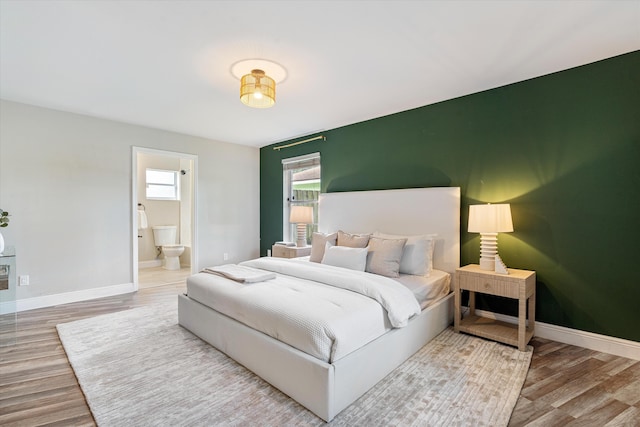 bedroom with hardwood / wood-style flooring and connected bathroom