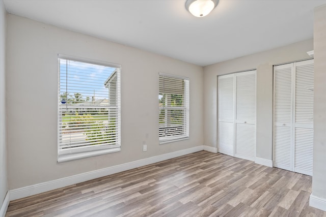 unfurnished bedroom featuring two closets and light hardwood / wood-style flooring