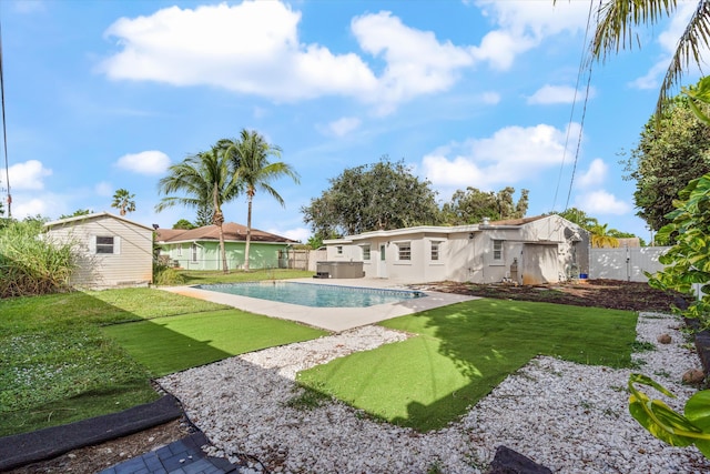 rear view of property featuring a fenced in pool, a shed, and a lawn