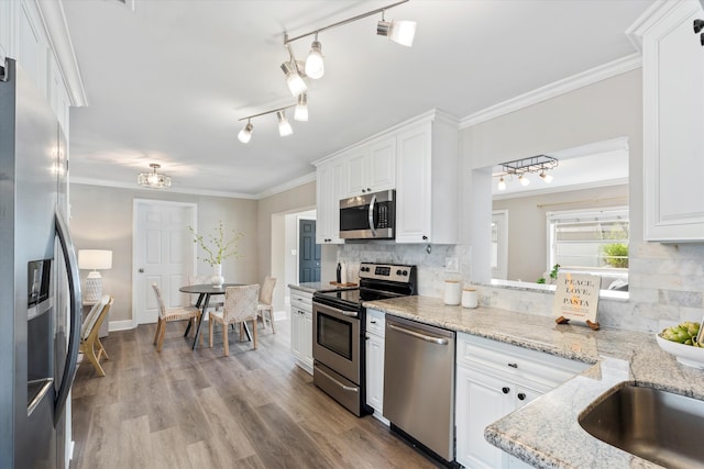 kitchen featuring white cabinetry, light stone counters, light wood-type flooring, appliances with stainless steel finishes, and decorative backsplash