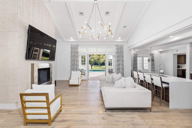 living room with a fireplace, sink, light hardwood / wood-style flooring, and beamed ceiling