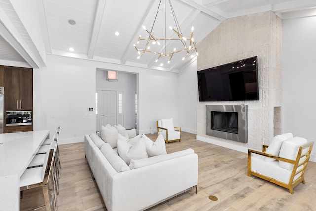 living room with light wood-type flooring, a chandelier, beam ceiling, a fireplace, and high vaulted ceiling