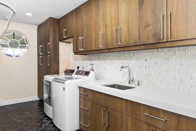 washroom with washing machine and clothes dryer, cabinets, and sink