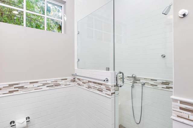 bathroom featuring tile walls and a shower with shower door