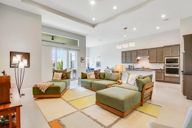 living room featuring ceiling fan, a towering ceiling, and sink