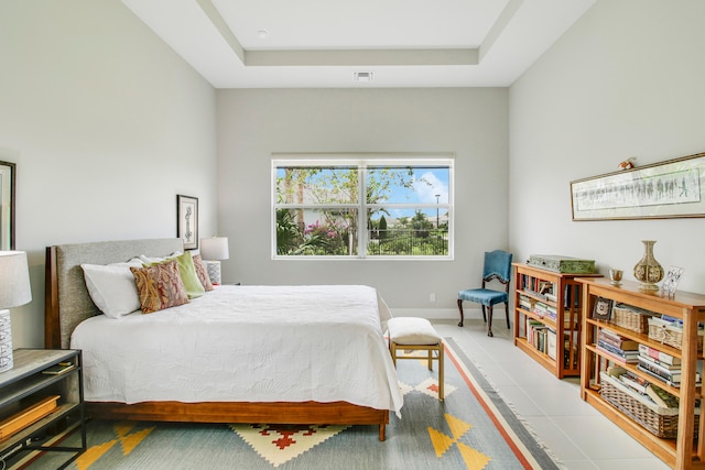 bedroom with a tray ceiling and light tile patterned floors