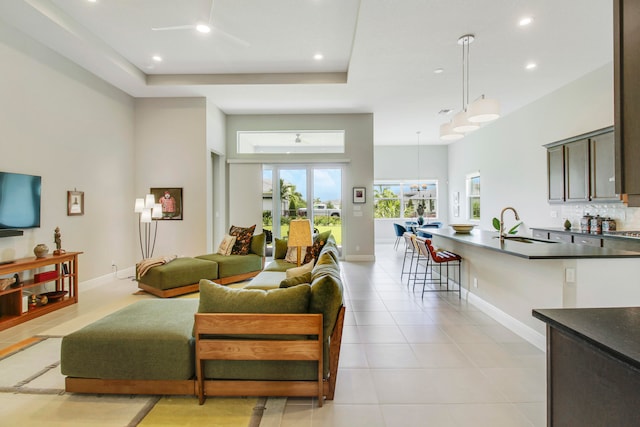 tiled living room featuring ceiling fan, sink, and a high ceiling