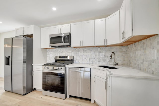 kitchen with backsplash, stainless steel appliances, light stone countertops, and light hardwood / wood-style flooring