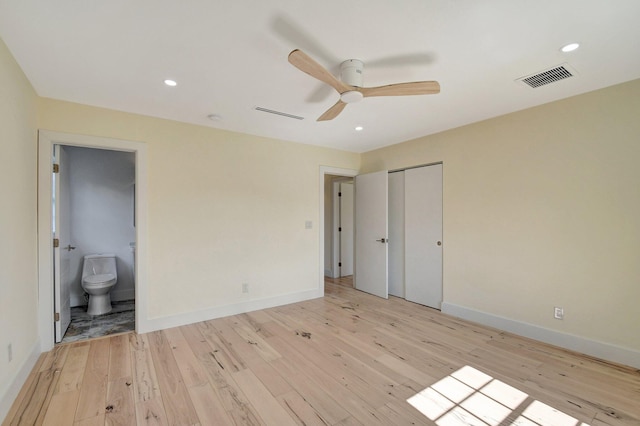 unfurnished bedroom featuring light wood-type flooring, a closet, ceiling fan, and ensuite bathroom