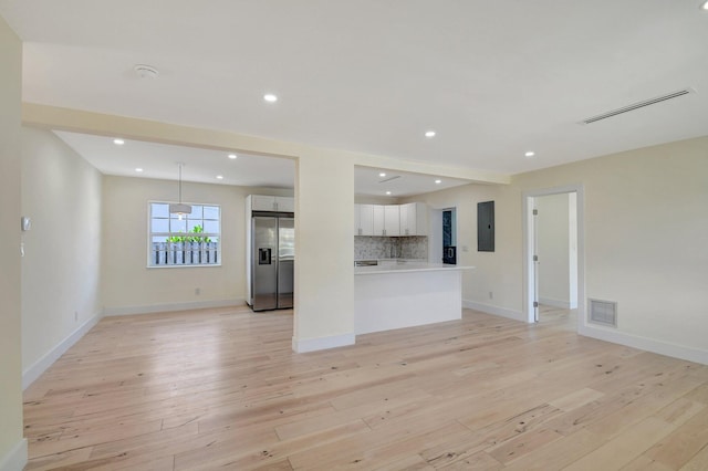 unfurnished living room with electric panel and light hardwood / wood-style flooring