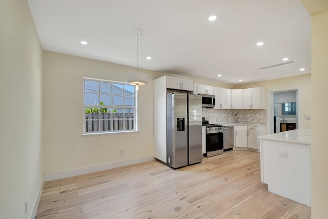 kitchen featuring light wood-type flooring, backsplash, stainless steel appliances, sink, and white cabinets