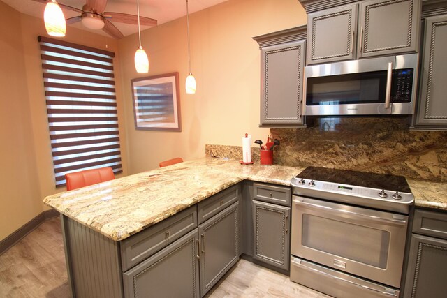 kitchen featuring light hardwood / wood-style floors, backsplash, stainless steel appliances, and kitchen peninsula