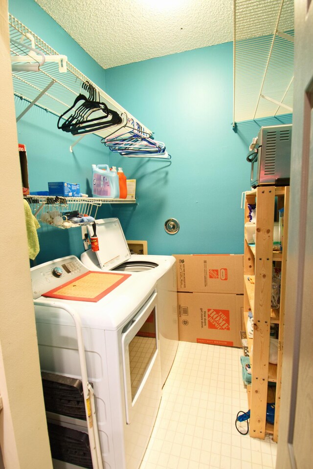 laundry room featuring independent washer and dryer, light tile patterned flooring, and a textured ceiling