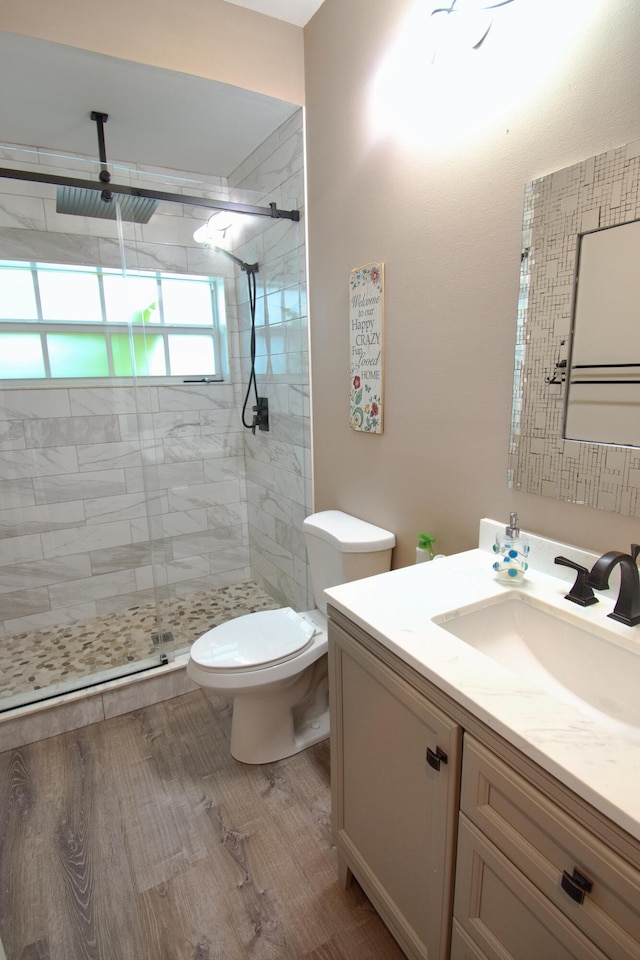 bathroom featuring hardwood / wood-style flooring, a shower with door, vanity, and toilet