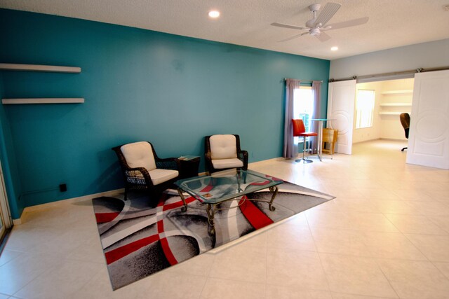 living area with ceiling fan, light tile patterned floors, and a textured ceiling