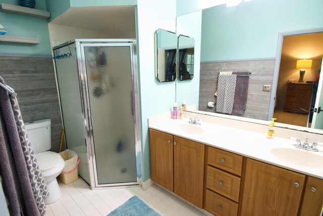 bathroom with a shower with door, tile patterned floors, toilet, and vanity