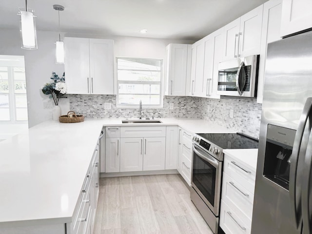 kitchen featuring appliances with stainless steel finishes, decorative backsplash, white cabinetry, sink, and light wood-type flooring