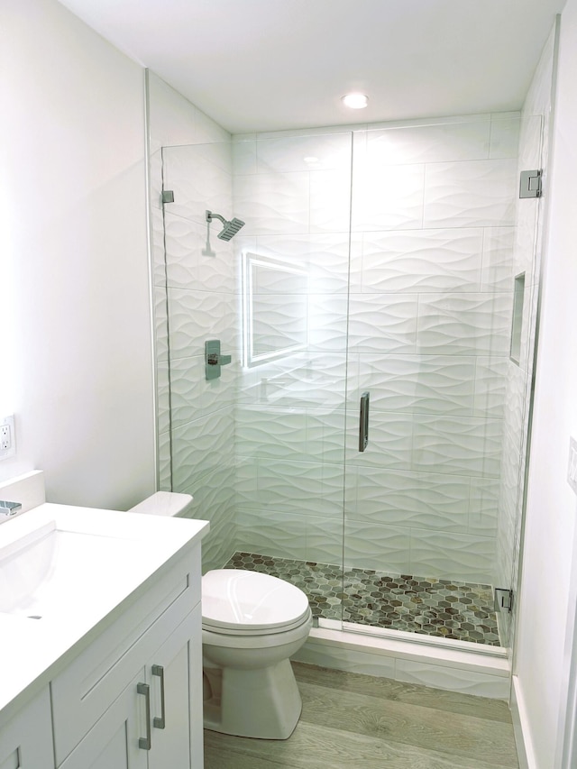 full bathroom with toilet, a shower stall, wood finished floors, and vanity