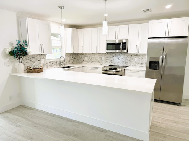 kitchen with light countertops, visible vents, appliances with stainless steel finishes, a sink, and a peninsula