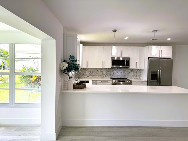 kitchen with a wealth of natural light, tasteful backsplash, pendant lighting, and stainless steel appliances