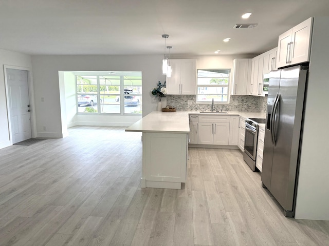 kitchen with a peninsula, a sink, light countertops, appliances with stainless steel finishes, and tasteful backsplash