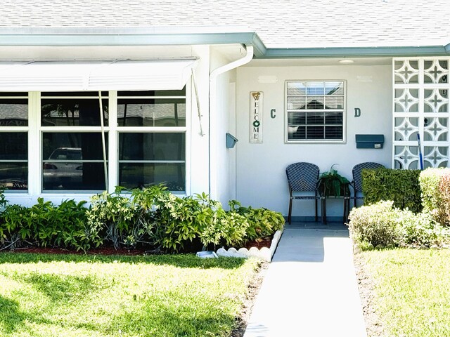 1090 N Dr Unit C, Delray Beach, FL 33445 - doorway to property with roof with shingles and a lawn