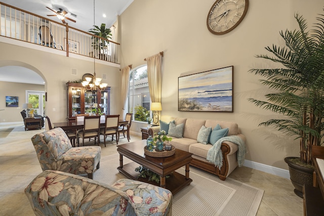 living room featuring a towering ceiling and ceiling fan with notable chandelier