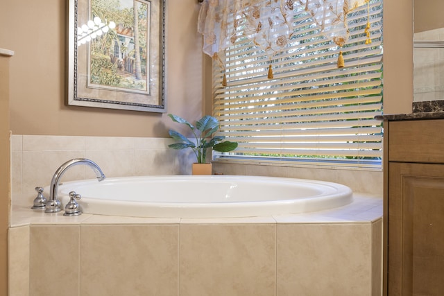 bathroom featuring tiled bath and vanity