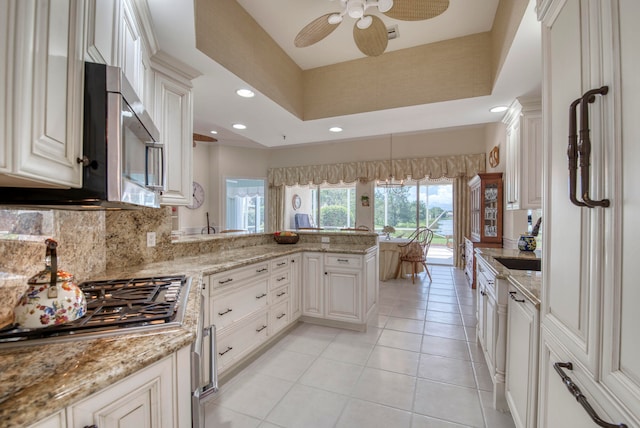 kitchen featuring light tile patterned flooring, backsplash, kitchen peninsula, white cabinets, and appliances with stainless steel finishes