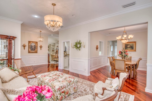 living room featuring hardwood / wood-style floors, an inviting chandelier, crown molding, and a healthy amount of sunlight