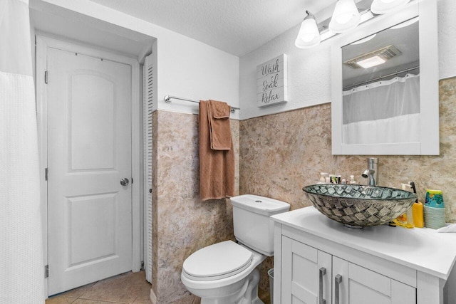 bathroom featuring tile patterned floors, toilet, a textured ceiling, and vanity