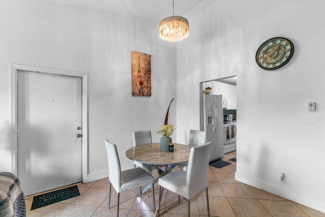 dining area featuring a high ceiling, light tile patterned floors, and a notable chandelier