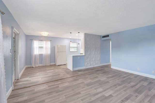 unfurnished living room with a textured ceiling and light hardwood / wood-style flooring