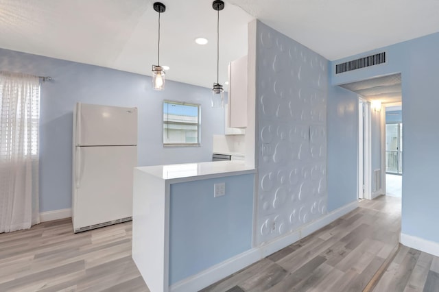 kitchen with white cabinetry, kitchen peninsula, pendant lighting, white fridge, and light hardwood / wood-style flooring