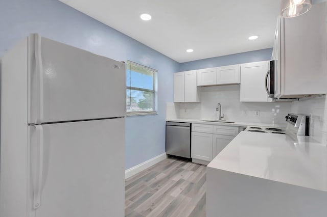 kitchen with sink, white cabinets, light hardwood / wood-style flooring, stainless steel appliances, and decorative light fixtures