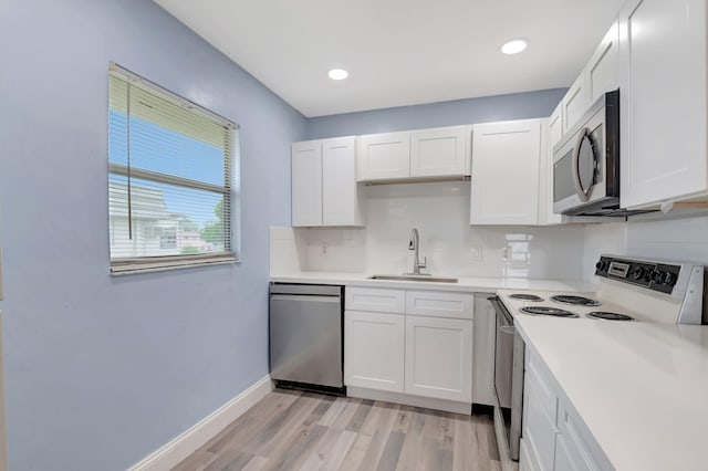 kitchen featuring sink, tasteful backsplash, white cabinetry, appliances with stainless steel finishes, and light wood-type flooring